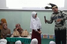 Pustakawan Ahli Muda Dispusarsip Sulsel, Zahir Juana Ridwan, S.Sos (kanan) yang mengenakan kemeja batik dan passapu, tampil bersenandung sambil mengajak salah satu murid menyenandungkan pantun di Perpustakaan Gerbang Ilmu SD Negeri Borong, Makassar, Selasa (6/10/2026).