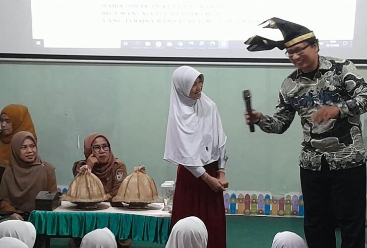 Pustakawan Ahli Muda Dispusarsip Sulsel, Zahir Juana Ridwan, S.Sos (kanan) yang mengenakan kemeja batik dan passapu, tampil bersenandung sambil mengajak salah satu murid menyenandungkan pantun di Perpustakaan Gerbang Ilmu SD Negeri Borong, Makassar, Selasa (6/10/2026).